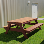 Hardwood A frame picnic table on grass with a building in the background