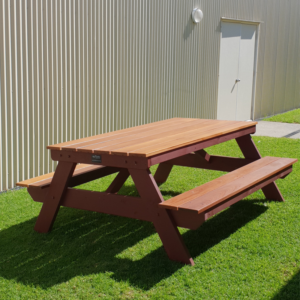 Hardwood A frame picnic table on grass with a building in the background