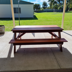 6 seater Jarrah picnic table on a concrete patio with grass and building in the background