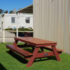 Hardwood A frame picnic table on grass with a building in the background