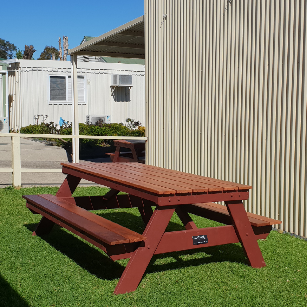 Hardwood A frame picnic table on grass with a building in the background