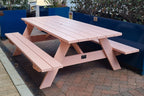 Pink A frame Pine picnic table with attached benches on a paved area